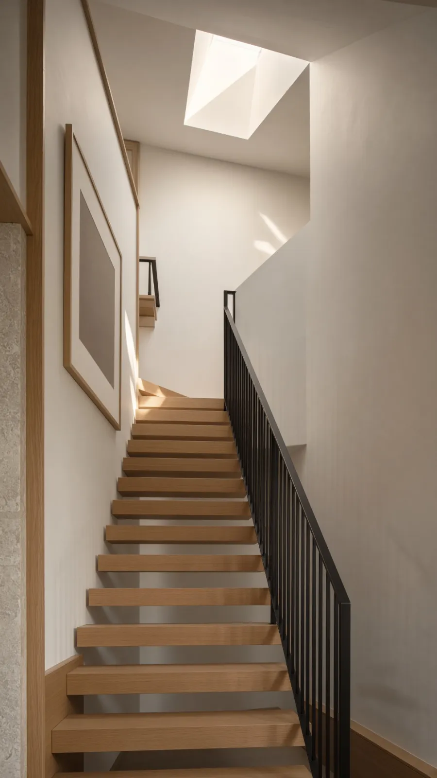A floating oak staircase lit from a skylight above.